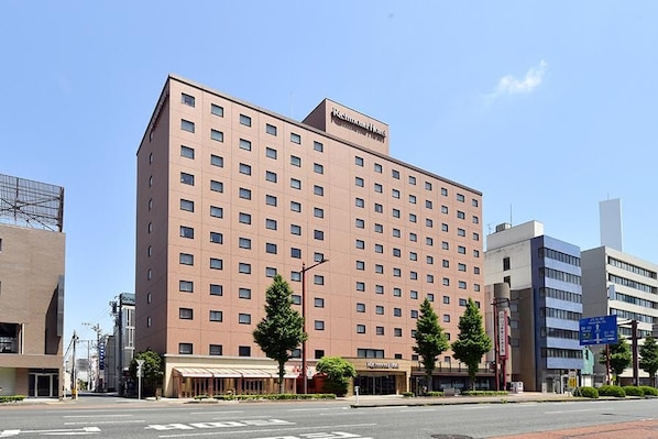 Un hotel de varios pisos con fachada uniforme, un letrero visible que indica que es un Richmond Hotel, y una calle despejada al frente.