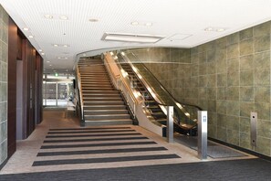 Un interior moderno con una escalera, una cinta transportadora y piso alfombrado.