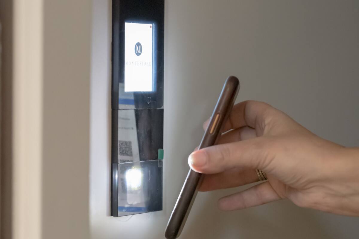 A hand holding a door handle, with a digital lock and a keypad visible in the background.