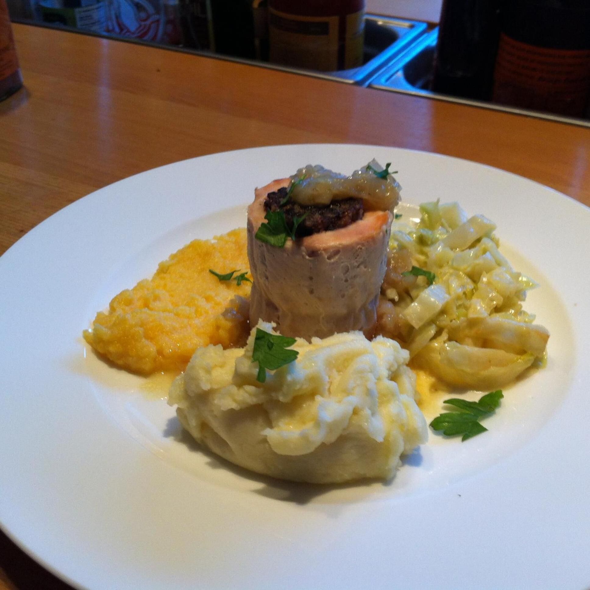 A plate with a meat dish, mashed potatoes, and dumplings.