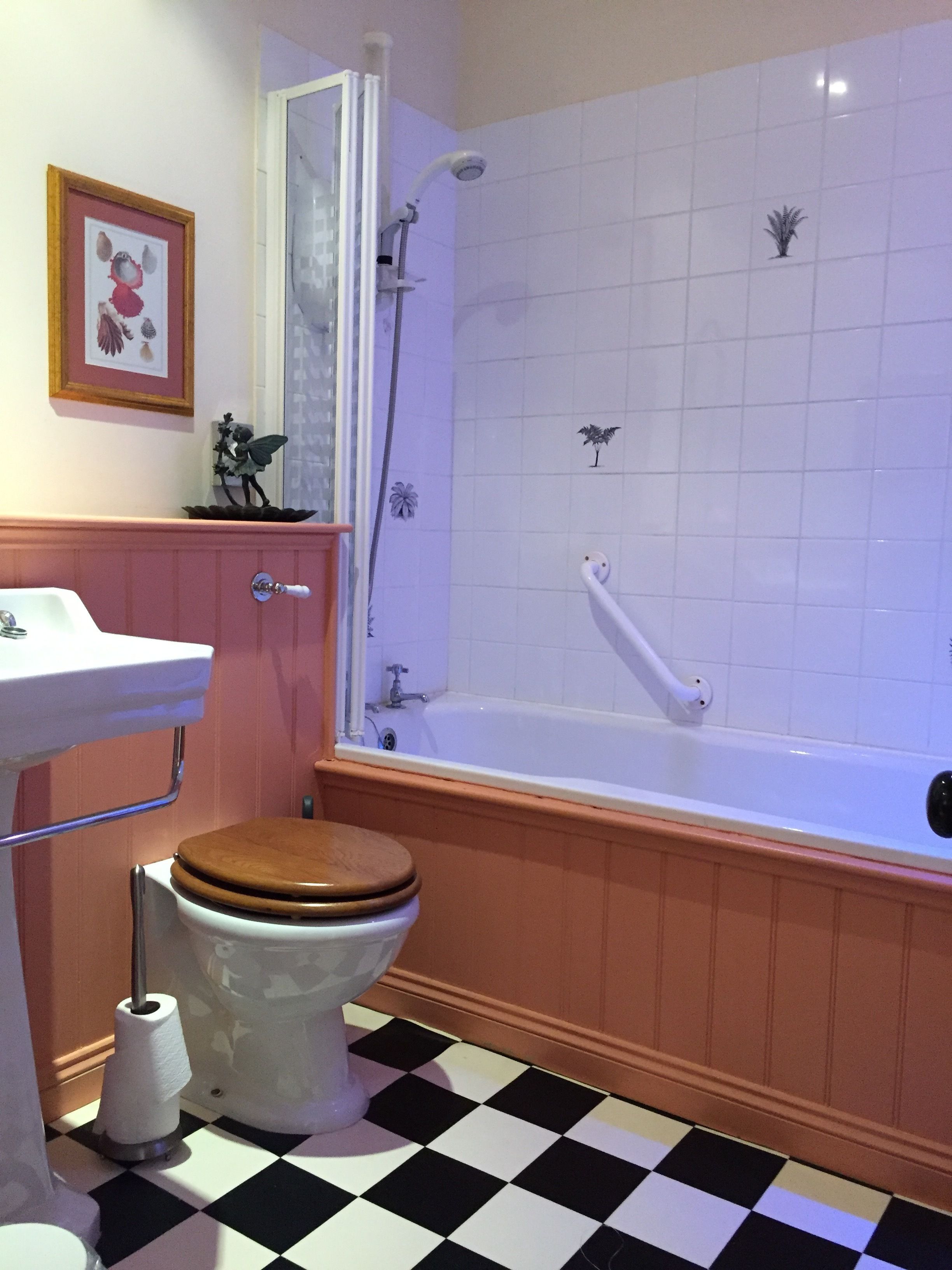 A bathroom with a white bathtub, a wooden toilet, a sink, and a shower.