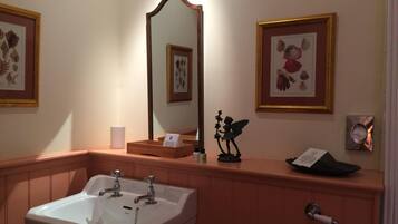 Un baño con lavamanos, espejo, una obra de arte enmarco y un pequeño adorno.