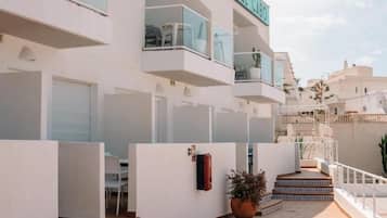 Un edificio moderno con balcones, un cartel que dice 'Hostal Del Cabo' y piso de baldosas.