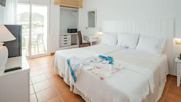 Habitación de hotel con una cama grande, un escritorio con lámpara, un armario y vistas al exterior.