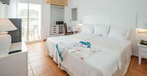 A hotel room with a large bed, a desk with a lamp, a wardrobe, and a view of the outdoors. - San Jose (Nijar)