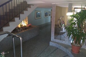Una escalera con barandilla de metal, una planta en maceta y cuadros colgados en la pared.