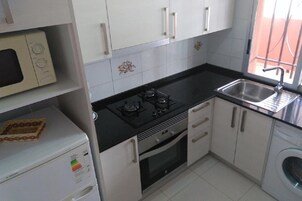 Una cocina compacta equipada con estufa, horno, microondas y lavaplatos.