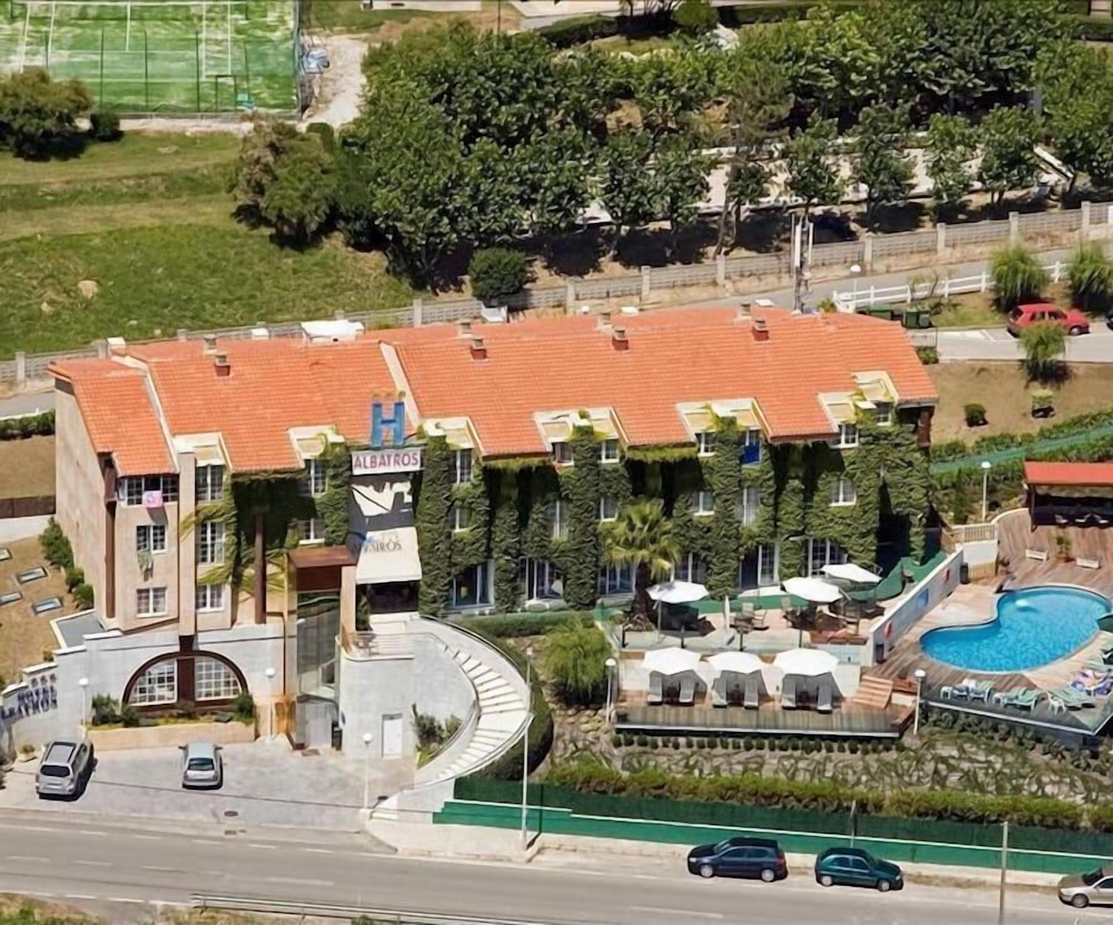 Un hotel con piscina, mobiliario de exterior y jardín ajardinado.