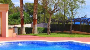 A swimming pool with a blue mosaic border, surrounded by a red deck and palm trees. - Gavina D Or (Mont-roig del Camp)