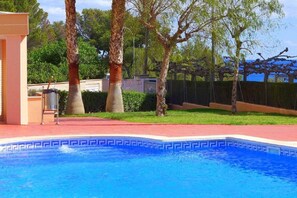 A swimming pool with a blue mosaic border, surrounded by a red deck and palm trees. - Gavina D Or (Mont-roig del Camp)