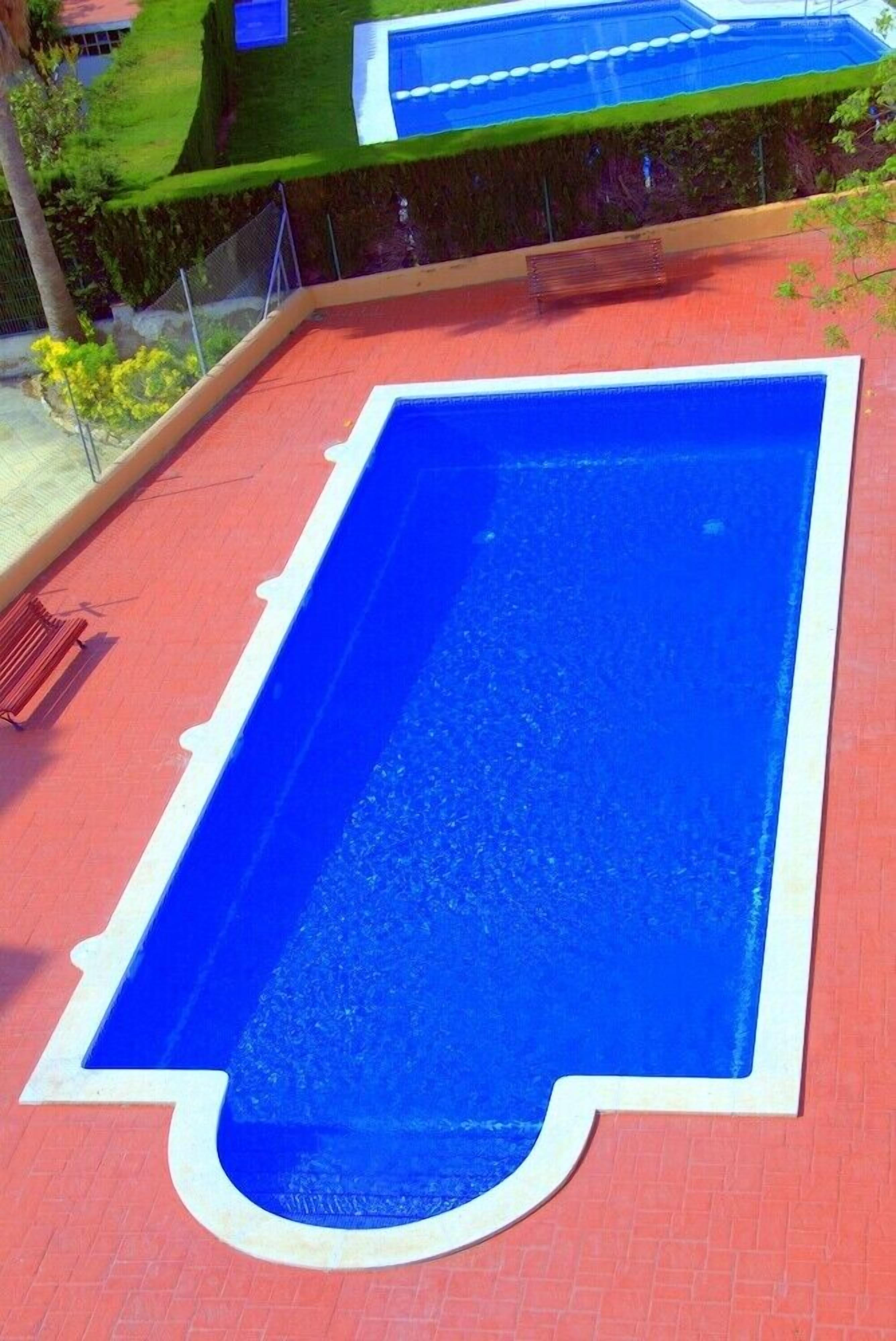 Ein rechteckiger Swimmingpool mit blauer Innenauskleidung und einem roten Deck.