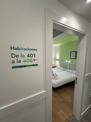 A hotel room with a bed, a nightstand, and a green wall. There is a sign indicating room numbers 401 to 406. - Hotel Virgen de Covadonga (Cangas de Onis)