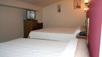 Een hotelkamer met twee bedden, een televisie op een houten kast en een schilderij aan de muur.