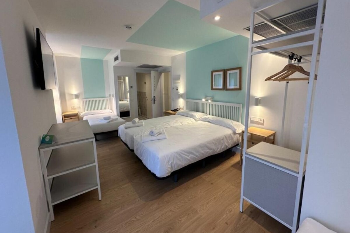 A hotel room with a bed, bedside tables, a wardrobe, and a desk.