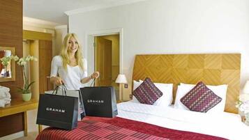 A hotel room with a bed, a nightstand, a lamp, and a window.