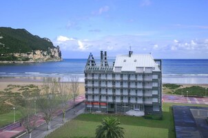 A hotel with a modern architectural design, located near a beach with a view of the ocean.