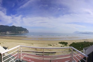 A beach with a clear view of the ocean and distant mountains.