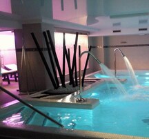 A spa area with a hot tub, a massage table, and a massage chair.