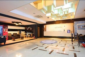 A modern hotel lobby with a reception desk, seating area, and a patterned floor. - Jeju Airport Hotel (Jeju City)