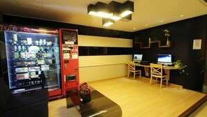Un hall d’hôtel moderne équipé d’un distributeur automatique, d’un comptoir d’accueil et d’un espace salon.