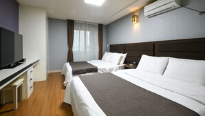 Une chambre d’hôtel avec deux lits, un bureau avec une télévision et un climatiseur fixé au mur.