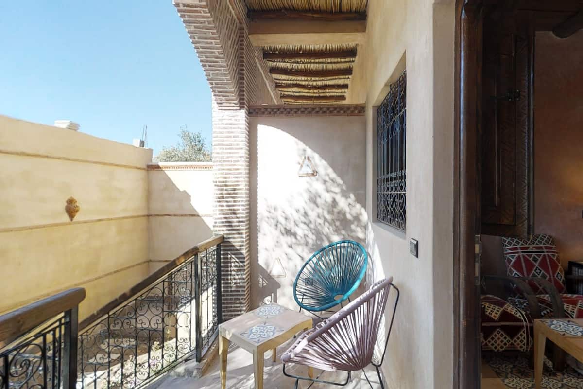 A balcony with a chair, a small table, and a patterned wall.