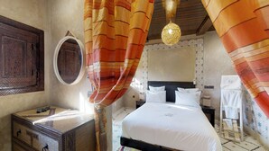 A hotel room with a bed, a bedside table, a mirror, and a hanging light fixture. - Ferme By Ikalimo (Sti Fadma)
