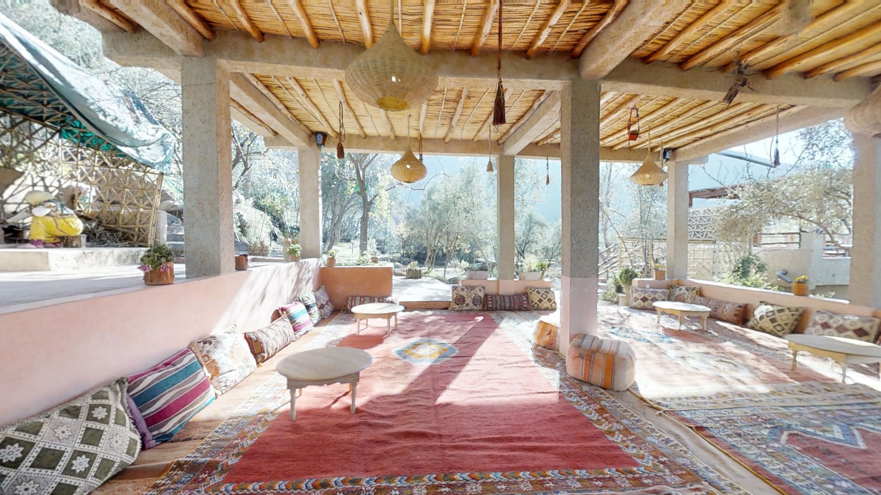 An outdoor patio with a red carpet, multiple seating areas, and hanging lights.