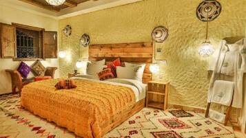 A cozy bedroom with a wooden headboard, a patterned bedspread, and a decorative rug.