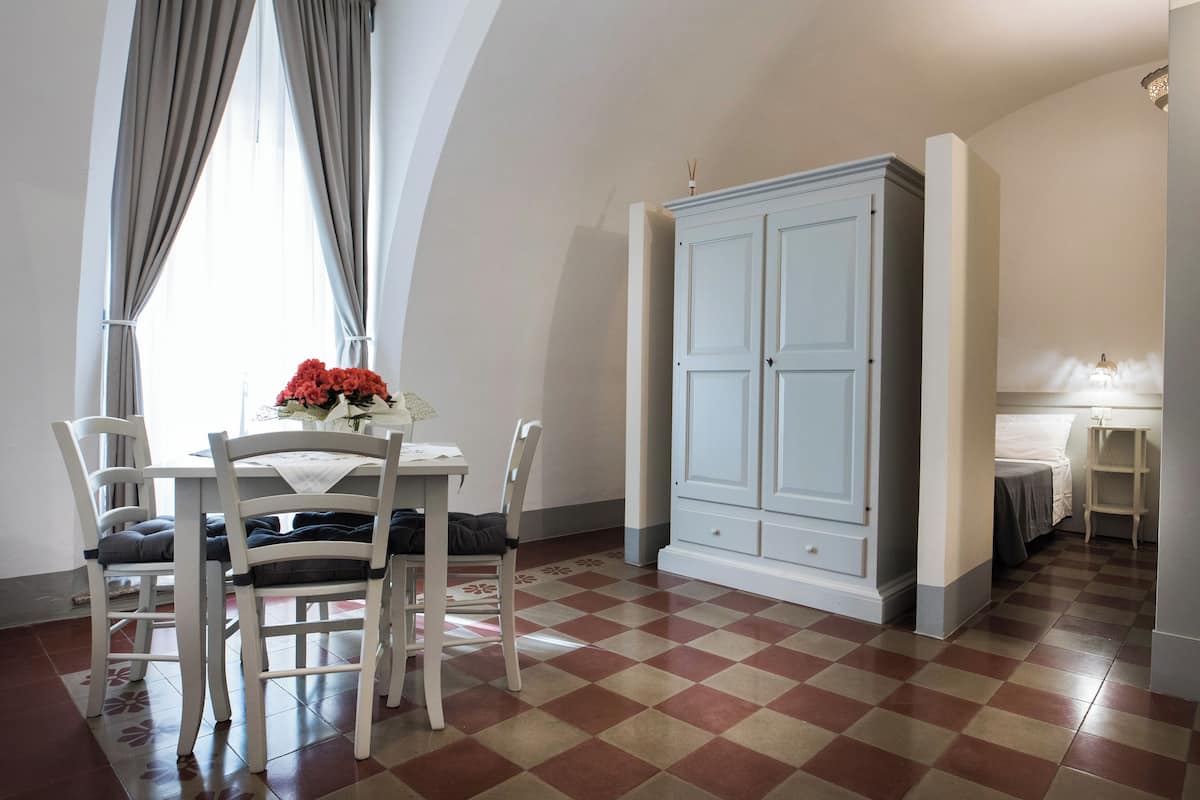 A dining area with a table and chairs, a large white wardrobe, and a checkered floor.