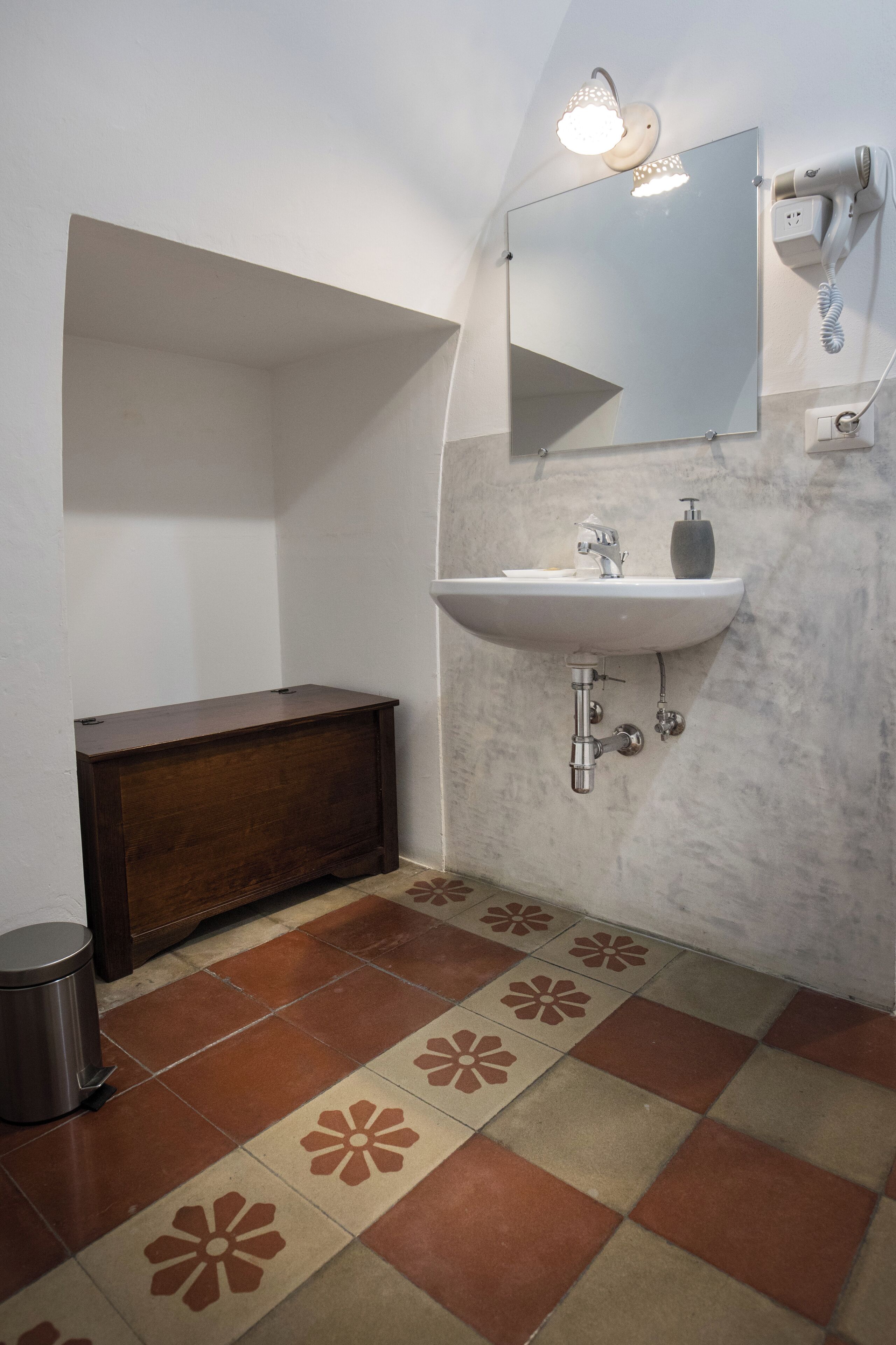 A bathroom with a sink, mirror, and hairdryer mounted on the wall.