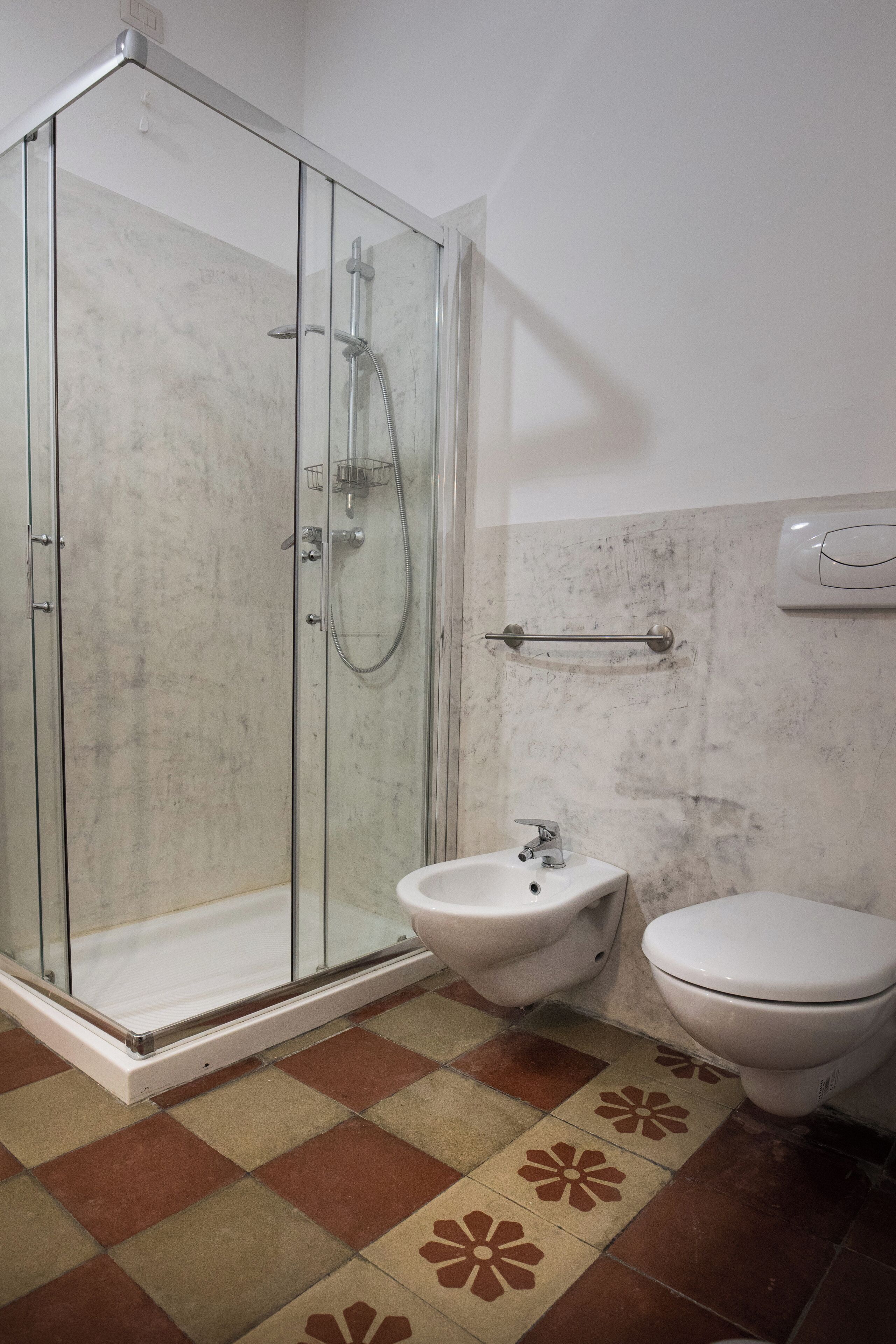 A bathroom with a glass shower enclosure, a sink, and a toilet.