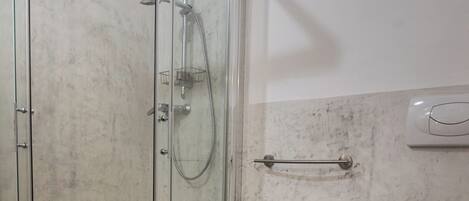 A bathroom with a glass shower enclosure, a sink, and a toilet.
