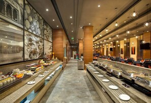 A buffet with multiple serving stations, a long corridor, and a wall with abstract art.