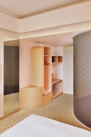 A modern hotel room with a large bed, built-in wardrobe, and a mirror.