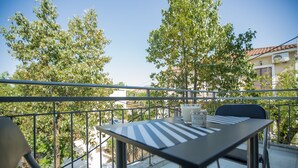 A balcony with a table and chairs, overlooking a residential area with trees and buildings. - Ilaeira rooms (Zakynthos)