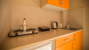 A kitchen with a gas stove, a kettle, salt and pepper shakers, and a coffee maker. - Ilaeira rooms (Zakynthos)