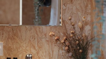 Ein Badezimmer mit einem weißen Waschbecken, zwei Flaschen mit brauner Flüssigkeit, einem silbernen Wasserhahn und einem Spiegel über dem Waschbecken.