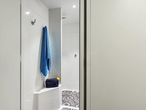 A bathroom with a shower, a towel rack, and a shelf with a towel and a bag. - Hotel F1 Cergy Pontoise (Cergy)