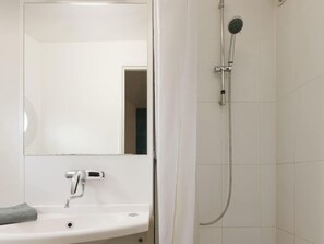 A bathroom with a white sink, a mirror, and a shower with a handheld showerhead. - Hotel F1 Cergy Pontoise (Cergy)