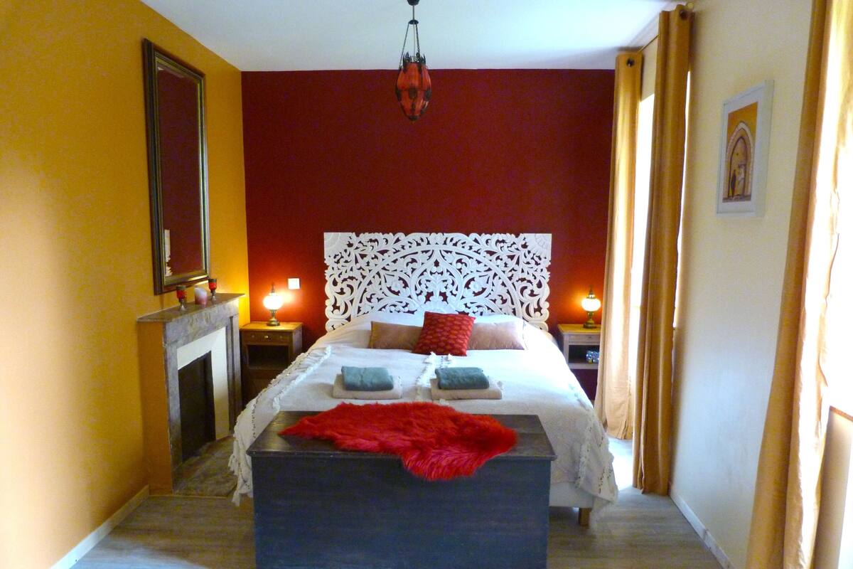 Ein Schlafzimmer mit Bett, Nachttischen, einem Spiegel und einem Kamin.