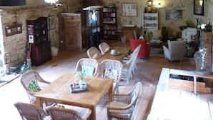 Un intérieur rustique avec des poutres apparentes, des meubles en osier et un mur en pierre.