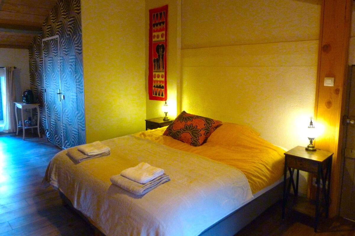 Ein Schlafzimmer mit einem Bett, zwei Nachttischen, einer Wandteppich und einer Tür.