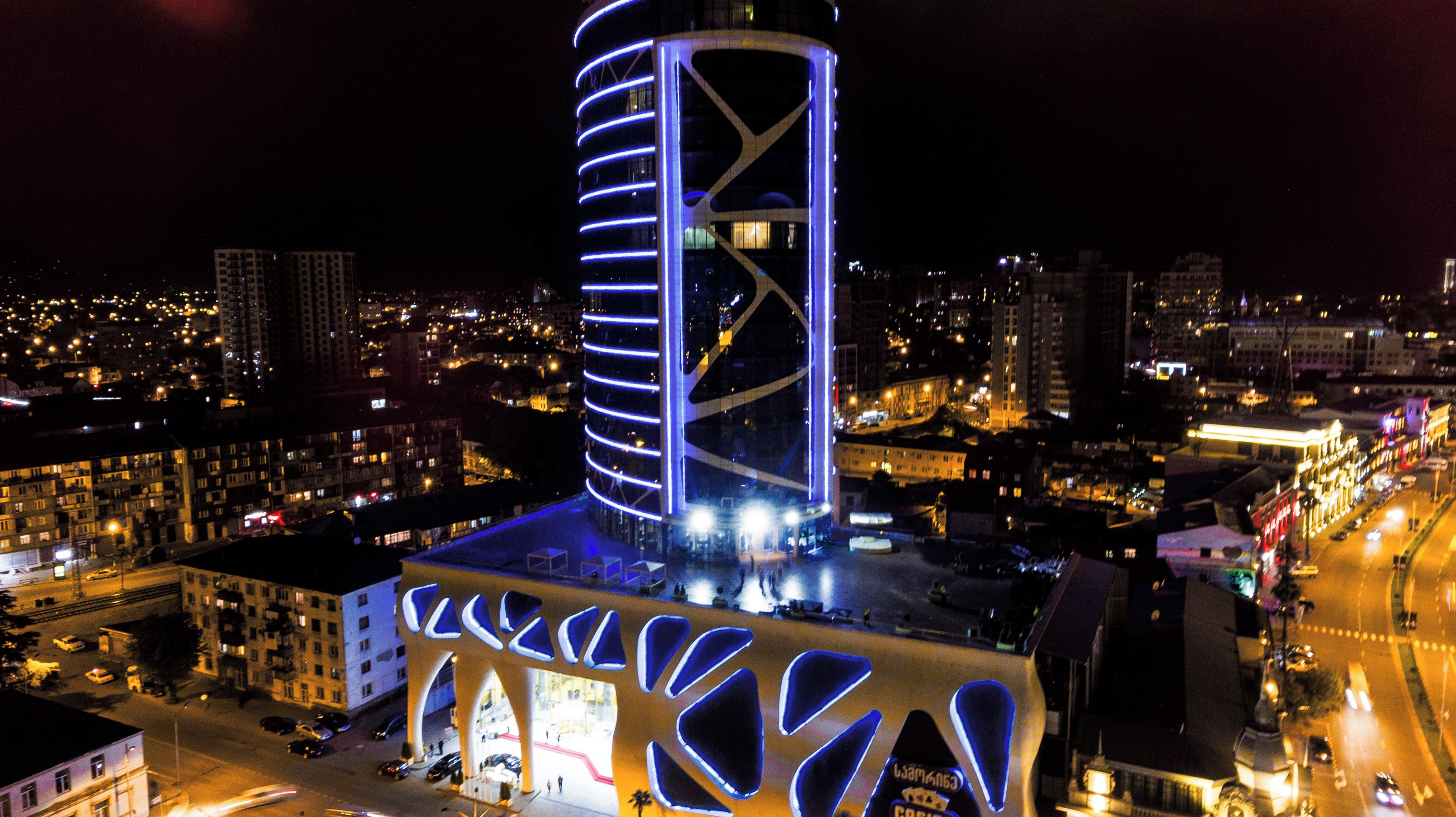 Un edificio moderno con un diseño arquitectónico único, que presenta una torre cilíndrica y una fachada con patrones geométricos.