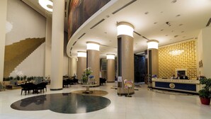 Vestíbulo de hotel con mostrador de recepción, zona de estar y un gran elemento decorativo en la pared.