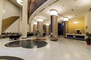 A hotel lobby with a reception desk, seating area, and a large decorative wall. - JRW Welmond Hotel (Batumi)