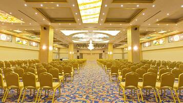 A conference room with rows of chairs, a patterned carpet, and a chandelier.