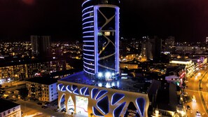 Een modern gebouw met een uniek architectonisch ontwerp, bestaande uit een cilindrische toren en een gevel met geometrische patronen.