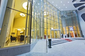 Een modern gebouw met grote glazen ramen, een duidelijke ingang en een rode loper naar de deur.