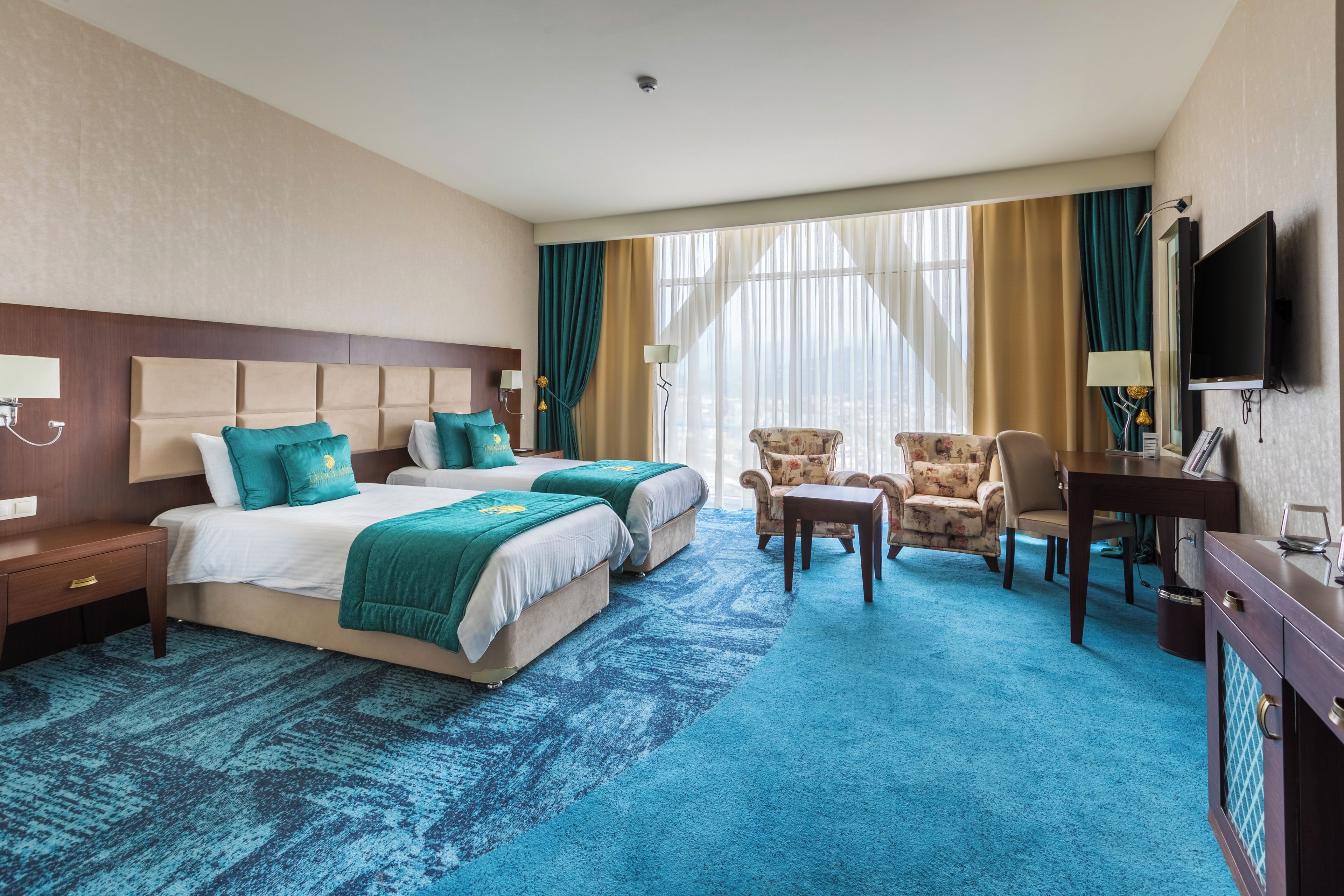 A hotel room with two beds, a TV, a desk, and a chair.